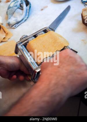 pasta caucasica per pasta cruda fatta in casa da macchinetta italiana a mano con farina di semola su marmo bianco Foto Stock