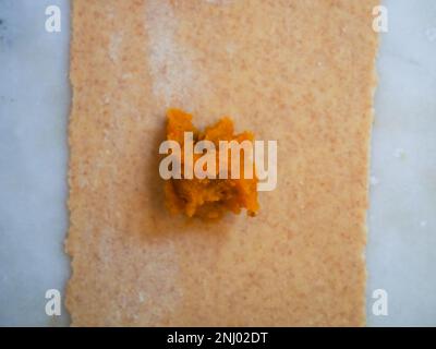 donna anziana che prepara tortelli di ravioli di zucca ripieni con farina di grano integrale italiana a casa, concetto di cibo fatto in casa Foto Stock