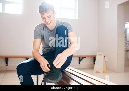 Sport, scarpe da legatura e uomo in spogliatoio per l'allenamento, fitness e palestra. Esercizio fisico, salute e inizio cardio con atleta e scarpe da ginnastica vestito Foto Stock