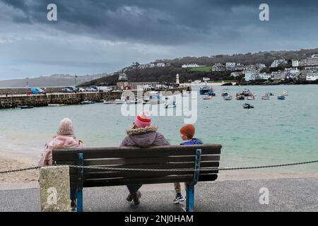 Meteo nel Regno Unito. I visitatori seduti su una panchina in una giornata piovosa e fredda nella storica cittadina costiera di St Ives, in Cornovaglia, in Inghilterra, nel Regno Unito. Foto Stock