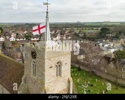 Vista aerea di una bandiera inglese di St Georges vista in cima alla torre della chiesa inglese del villaggio. Si vede il bel tetto a piombo sulla torre. Foto Stock