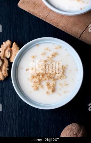 Crema pasticcera fatta in casa con noce, dessert turchi muhallebi su uno sfondo di legno. Crema fatta in casa con noce. Foto Stock