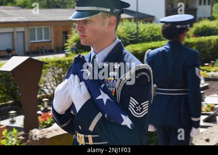 Un membro del servizio della Guardia d'onore della base aerea di Spangdahlem, Germania, tiene una bandiera americana piegata durante il funerale per gli Stati Uniti Veterano dell'aeronautica, in pensione il maggiore Gary Retterbush al cimitero di Eisenschmitt, Eisenschmitt, Germania, 4 agosto 2022. STATI UNITI Air Force F-16 Fighting Falcons, assegnato al 480th Fighter Squadron, ha eseguito una formazione di dispersi durante il funerale. Foto Stock