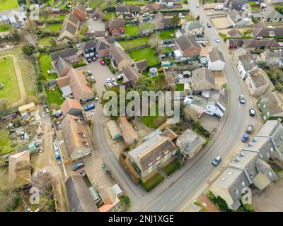 Veduta aerea di una parte di un tipico villaggio inglese, che mostra la strada principale che serpeggiante nel villaggio High Street in basso a sinistra. Foto Stock