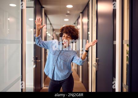 Felice giovane Businesswoman celebrare Danza lungo Corridoio in Ufficio moderno Foto Stock