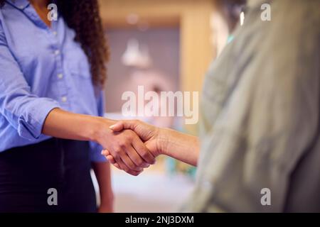 Primo piano di due Businesswomen incontro e scuotere le mani nel moderno Open Plan Office Foto Stock