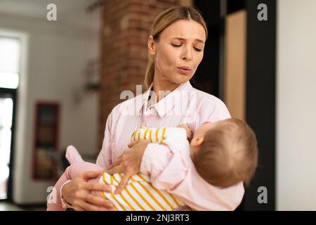 Madre affettuosa che tiene in mano la bambina, lulling che dorme il bambino, godendosi giorno spensierato e silenzioso a casa Foto Stock