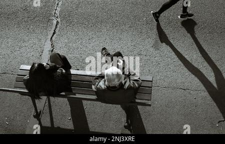 Vista guardando giù su due persone, uomo e donna seduto su Una panchina con Un Jogger che corre passato sulle rive del fiume Senna, Parigi Francia Foto Stock