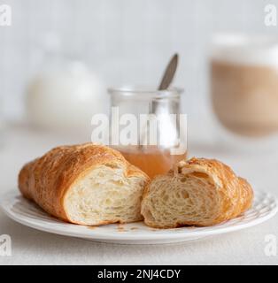 croissant con marmellata di pere per la prima colazione con una tazza di caffè e latte. Colazione francese Foto Stock