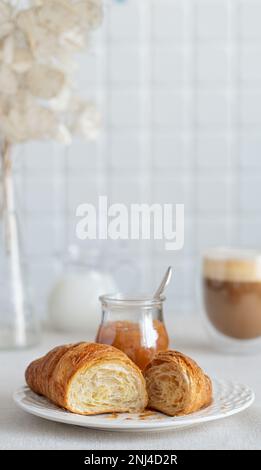 croissant con marmellata di pere per la prima colazione con una tazza di caffè e latte. Colazione francese Foto Stock