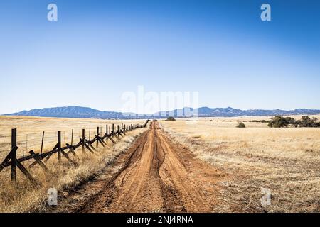 Una strada solitaria sterrata attraverso le praterie lungo il confine tra gli Stati Uniti e il Messico in Arizona. Foto Stock