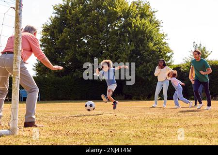 Famiglia Multi-Generation a casa in giardino giocare a calcio o calcio insieme Foto Stock