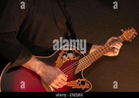 Vaduz, Liechtenstein, 13 gennaio 2023 l'artista suona con una chitarra acustica Ovation in rosso Foto Stock