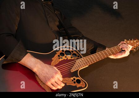 Vaduz, Liechtenstein, 13 gennaio 2023 l'artista suona con una chitarra acustica Ovation in rosso Foto Stock