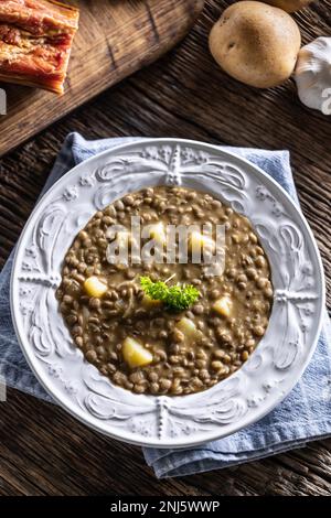 Zuppa di lenticchie e patate o stufato in un piatto rustico decorato con prezzemolo - Top of view. Foto Stock