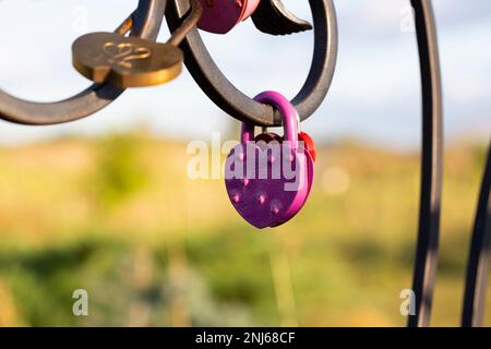 La serratura a forma di cuore rosa si appende dalla catena del ponte, la consuetudine di nozze è simbolo dell'amore eterno, copia spazio Foto Stock