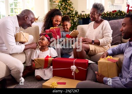 Famiglia Multi-generazione che celebra Natale a casa presenta di apertura insieme Foto Stock