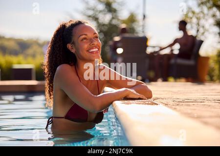 Donna sorridente in vacanza estiva relax in piscina Foto Stock