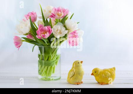 Bouquet pasquale di tulipani primaverili e decorazioni pasquali su tavolo di legno bianco. Concetto di Pasqua con spazio di copia. Foto Stock
