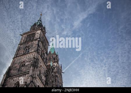 Sotto la vista di St Lorenz a Norimberga con cielo blu con nuvole. St Lawrence è una chiesa medievale in Baviera. Chiesa luterana storica in Germania. Foto Stock