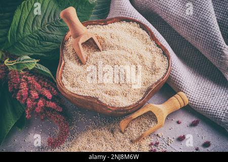 Granate di Amaranth in una ciotola di legno con ramatura in fiore amaranto, primo piano con fuoco selettivo, vista dall'alto Foto Stock