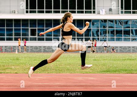 giovane atleta tripla salto in pista stadio Foto Stock