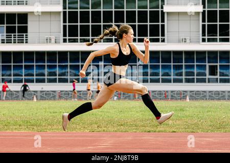 giovane atleta che salta in pista Foto Stock