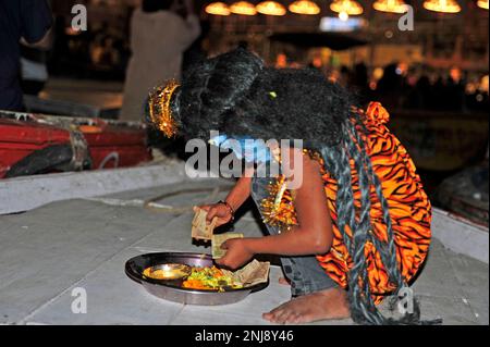 Bambina in costume tradizionale e faccia dipinta come il dio indù Shiva raccogliere denaro dai turisti. Varanasi - India Foto Stock