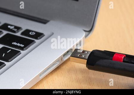 Una foto concettuale del collegamento di un'unità flash USB a un computer portatile. Foto Stock