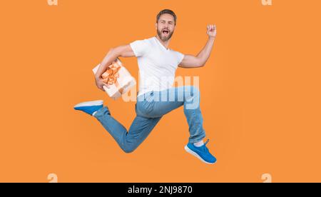 Presentare il corriere a mezz'aria. Ragazzo attivo che corre veloce con la scatola presente. Consegna di regali e regali Foto Stock