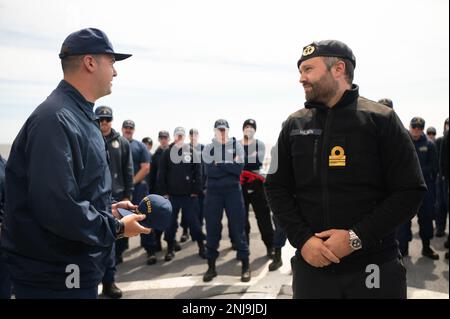 STATI UNITI Guardia costiera Lt. CMdR. Jason Lassiter, il responsabile operativo dell'orso USCGC (WMEC 901), consegna al Royal Norwegian Navy Officer Havard Nilsen una copertura ufficiale dell'orso a quarti per darlo formalmente il benvenuto a nome dell'equipaggio, Oceano Atlantico settentrionale, 6 agosto 2022. Nilsen è incorporato con l'orso attraverso operazione Nanook e rimarrà a bordo per la maggior parte della pattuglia restante. Foto Stock