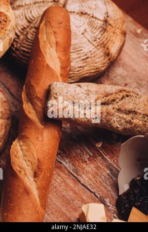 Un assortimento di pane artigianale appena sfornato sistemato su un tavolo di legno Foto Stock