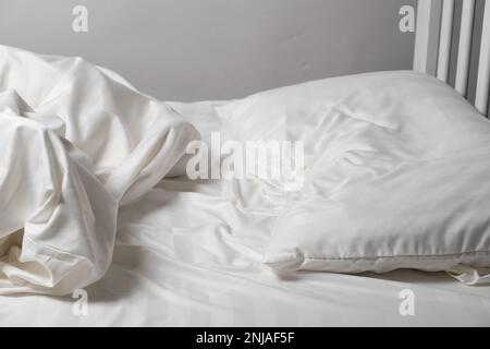 Letto non fatto in casa, lenzuola bianche in raso, letto bianco, cuscino e coperta Foto Stock