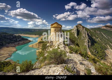 Eremo di la Pertusa su una scogliera sopra il bacino idrico di Canelles con pochissima acqua durante la siccità del 2022 (la Noguera, Lleida, Catalogna, Spagna) Foto Stock