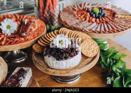Un tavolo di legno con una varietà di formaggi disposti su piatti e ciotole Foto Stock