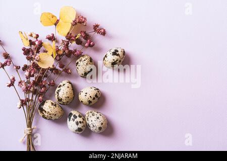 Uova e un bouquet di fiori primaverili su sfondo viola Foto Stock