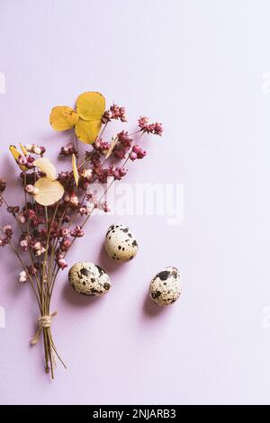 Uova di quaglia e un bouquet di fiori primaverili su sfondo viola Foto Stock