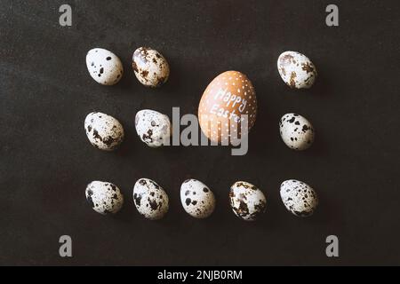 Felice uova di pasqua piatto giaceva su rustico metallo sfondo nero. Quaglia e uova di pollo allineate in fila a forma di rettangolo Foto Stock