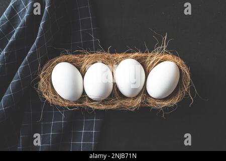 Uova allineate in fila in un nido su sfondo nero rustico Foto Stock