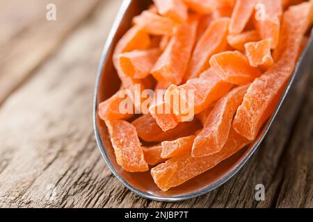 Bastoncini di papaya canditi o glacé in metallo su legno (fuoco selettivo, fuoco sull'estremità anteriore dei bastoncini di papaya) Foto Stock