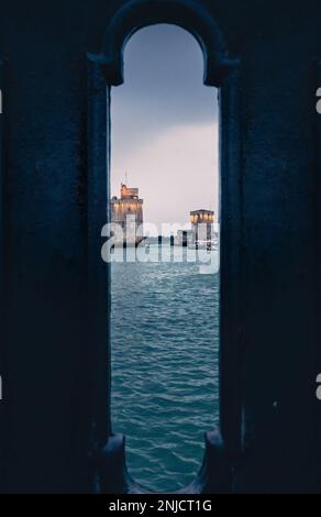 Vista attraverso la balaustra del vecchio porto di la Rochelle all'ora blu con le sue famose vecchie torri. Foto Stock