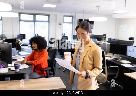 Donna d'affari asiatica con documenti e caffè che lavora in ufficio Foto Stock