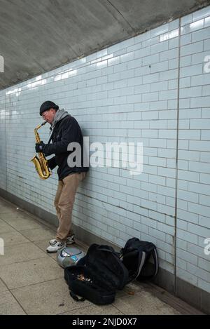 Busker suona il sassofono nella stazione della metropolitana di Londra Foto Stock