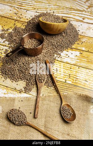 Vita morta con lenticchie secche su cucchiai di legno, pentola di rame da misurare su tavola di legno Foto Stock