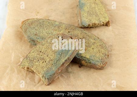 Fette di pane raffermo con muffa verde su White Table. Pane guastato con muffa. Fungo ammuffito su pane Rotten. Vista frontale. Foto Stock