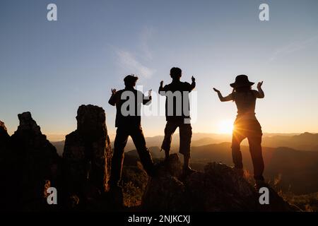 Silhouette di persone che pregano sulla montagna all'alba, sessione di terapia di gruppo, squadra cristiana religiosa pregare insieme per il recupero dare psicologico Foto Stock