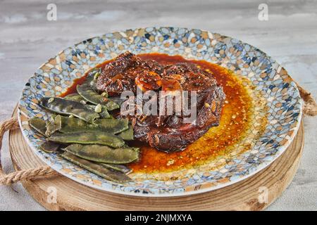 Agnello confit con piselli di neve in salsa sul piatto. Foto Stock