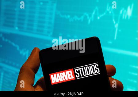 Cina. 15th Feb, 2023. In questa foto, il logo Marvel Studios, marchio americano di produzione cinematografica di proprietà di Disney, viene visualizzato su uno smartphone con un grafico di indice di borsa economica sullo sfondo. Credit: SOPA Images Limited/Alamy Live News Foto Stock