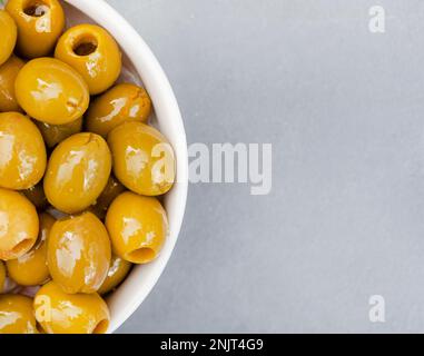 olive verdi snocciolate su una superficie bianca testurizzata con spazio di copia Foto Stock