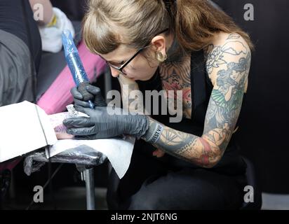 Cracovia, Polonia - 12 giugno 2022: Partecipante non identificato alla Convention Tattoofest 15th di Cracovia. Artista tatuaggio al lavoro. Foto Stock